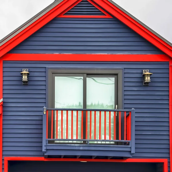 Vierkant frame close-up van huis exterieur met levendige blauwe muur rode frames en een klein balkon — Stockfoto