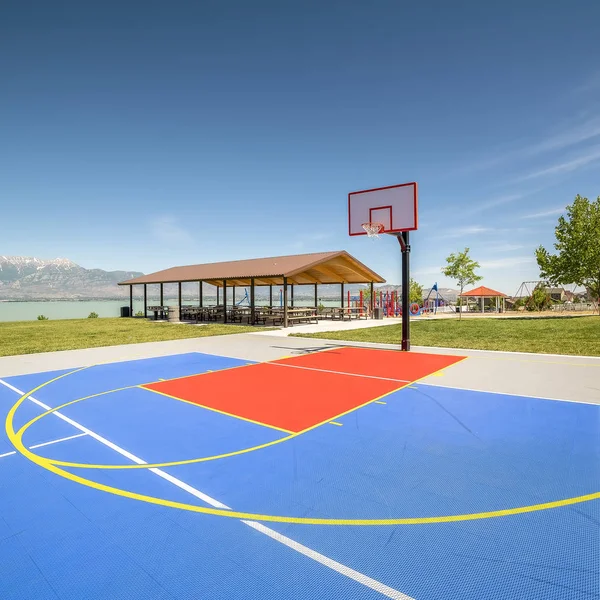 Square frame Outdoor basketball court with a picnic pavilion and playground in the background
