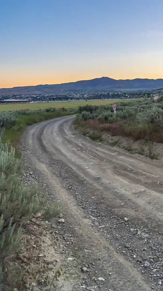 Quadro vertical Curva estrada de terra com vista para o vale e montanha contra o céu azul — Fotografia de Stock