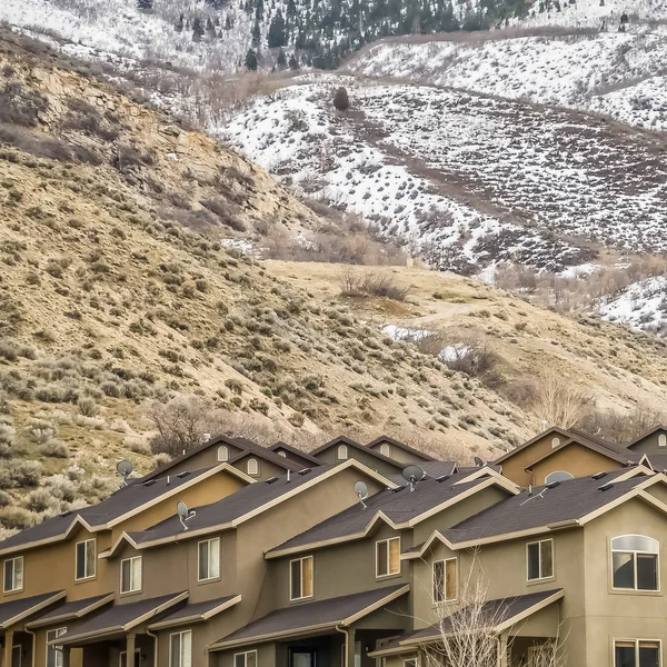 Kwadratowa rama widok z zewnątrz domów z śnieżnobiałe góry i zachmurzone tło nieba — Zdjęcie stockowe