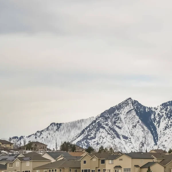 Carré Neige frappante plafonné des maisons de montagne et de plusieurs étages sous le ciel couvert — Photo