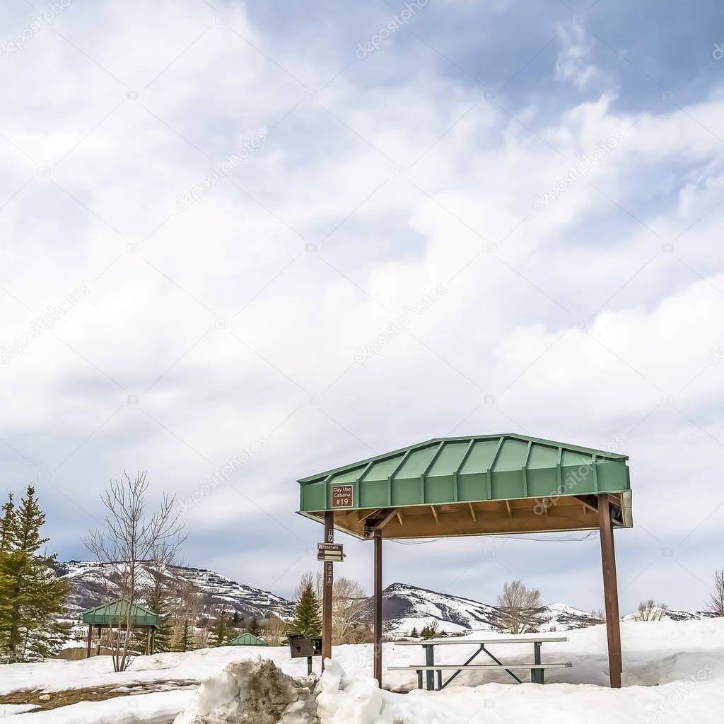 Square frame Park cabanas with view of snow covered mountain and cloudy blue sky in winter