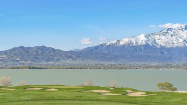 Panoramik çerçeve Güneşli bir günde mavi gökyüzü altında göl ve çimenli alan Manzara görünümü