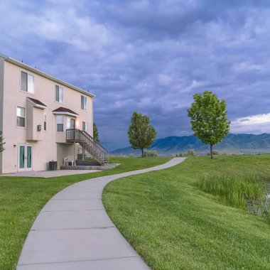 Çimenli bir alanda bir gölet ve patika bakan bir ev ile Kare Manzara manzara