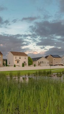 Balkonlu dikey çerçeve Evler ve çimenli gölet köprü ve geniş yeşil alan manzaralı