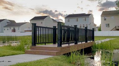 Gün batımında bir ağaç evler ve coudy gökyüzü manzaralı küçük bir gölet üzerinde Panorama çerçeve Köprü