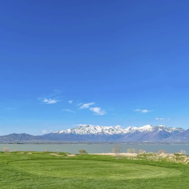 Sakin bir göl ve yüksek kar dağ tepesinde manzaralı yemyeşil çimenli arazi