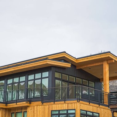 Kare Balkon parlak pencereler ve gri ve kahverengi ahşap duvar ile bir evin Dış