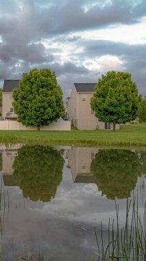 Çok katlı evlerin yansıması ile Dikey Gölet yemyeşil ağaçlar ve bulut dolu gökyüzü