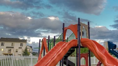 Bir çit ve evler karşı slaytlar salıncak masa ve koltuk ile Panorama Playground