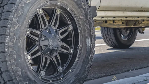 Marco panorámico Rueda de goma negra de un vehículo plateado estacionado en la carretera en un día soleado —  Fotos de Stock