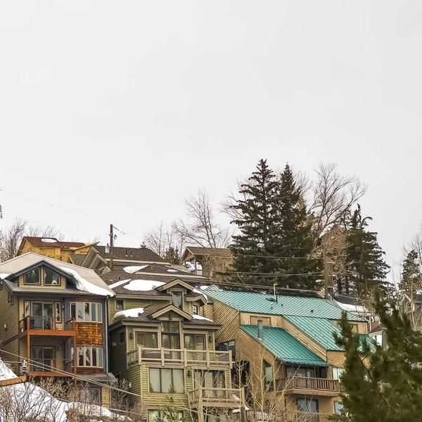 Marco cuadrado Casas de colina con balcones y techos nevados contra el cielo nublado en invierno — Foto de Stock