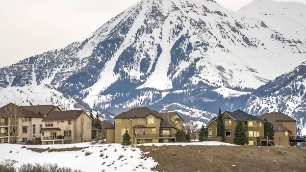Cadre panoramique Quartier construit sur une colline surplombant une montagne enneigée en hiver — Photo