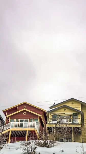 Rama pionowa rozległe zachmurzone niebo nad kolorowymi domami i śniegiem pokrytym ziemią zimą — Zdjęcie stockowe