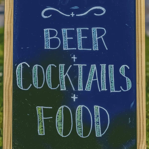 Square frame Close up of chalkboard menu sign against grassy sidewalk and road on a sunny day — Stock Photo, Image