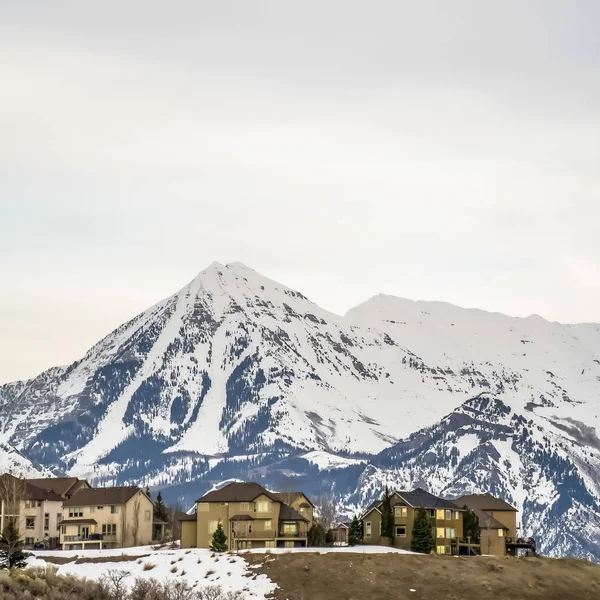 Quadratische Häuser auf einem Hügel mit Blick auf markante, im Winter mit Schnee bedeckte Berge — Stockfoto