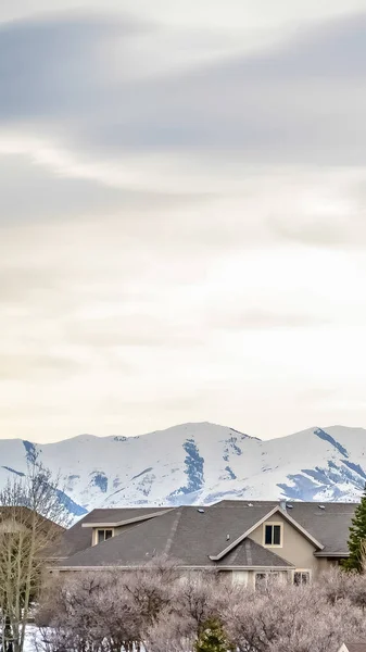 Dikey çerçeve Mahalle kışın karla kaplı dağ ve bulutlu gökyüzü arka plan — Stok fotoğraf
