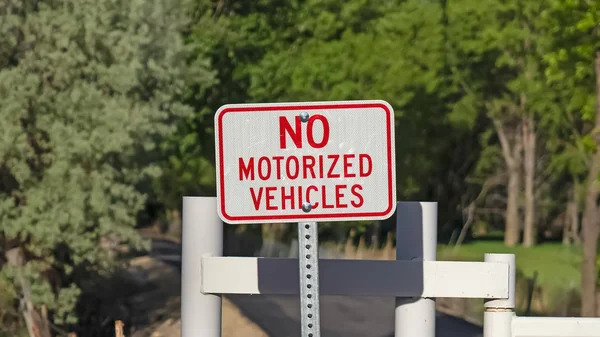 Marco panorámico No hay señal de vehículo motorizado contra una puerta blanca y una carretera estrecha en un día soleado — Foto de Stock