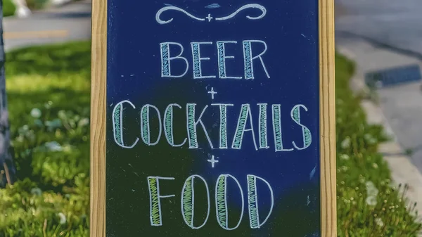 Panorama frame Close up of chalkboard menu sign against grassy sidewalk and road on a sunny day — Stock Photo, Image