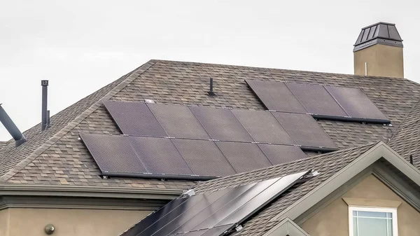 Panorama Paneles solares en el techo oscuro de una casa con fondo nublado del cielo — Foto de Stock