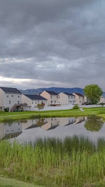 Balkonlu güzel evlerin önünde çimenli bir parkta köprü ile Dikey Parlak gölet