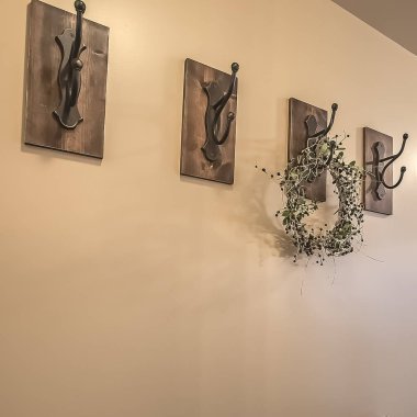 Kare çerçeve Ahşap dolaplar ve beyaz zeminli bir evin bej duvara karşı demir kancalar