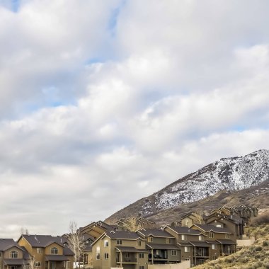 Kabarık bulutlar ile dolu mavi gökyüzü altında çok katlı dağ evleri Kare çerçeve Satır