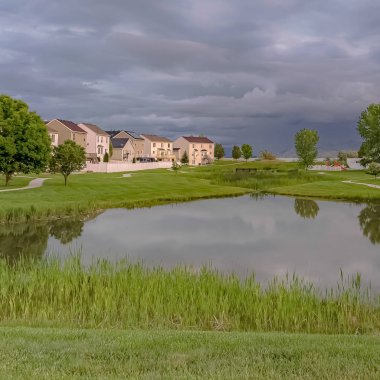 Güzel çok katlı evlerin ortasında gölet ve yollar ile Square Grassy park