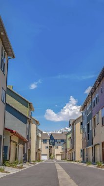 Güneşli bir günde mavi gökyüzünün altında ortasında asfalt yol ile evlerin Dikey çerçeve Satırlar