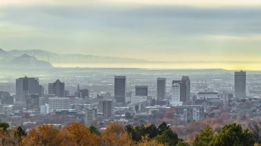 Bulutlu gökyüzü altında binalar ve karlı dağ ile kalabalık şehrin Panorama Panorama