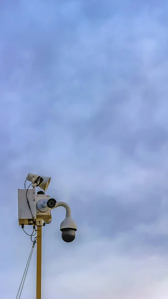 Quadro vertical Câmera de segurança ao ar livre isolada contra um fundo de céu azul nublado — Fotografia de Stock