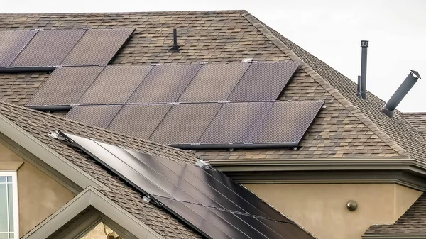 Panorama Paneles solares en el techo oscuro de una casa con muro de piedra y hormigón — Foto de Stock