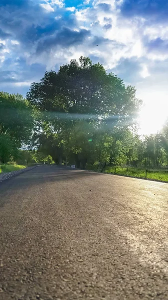 Κάθετη κλείσιμο ενός πλακόστρωτου δρόμου που φωτίζεται από τον φωτεινό ήλιο στον θολό γαλάζιο ουρανό — Φωτογραφία Αρχείου
