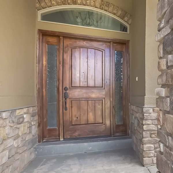 Marco cuadrado Fachada de casa con puerta de madera marrón esmerilados laterales y ventana abovedada — Foto de Stock