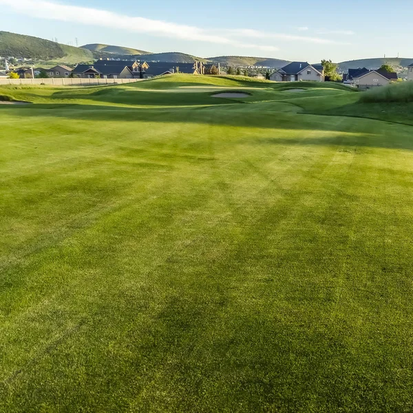 Square Fairway and bunkers of a golf course with homes and mountain in the distance — Stock Photo, Image