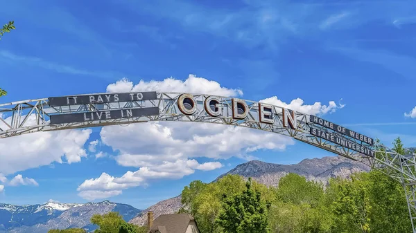 Panorama Welcome arch at the city of Ogden Utah against vivid blue sky and puffy clouds