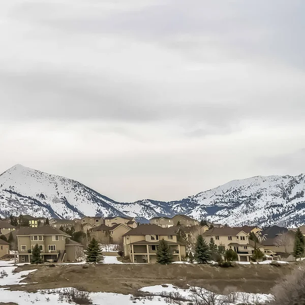 Paysage hivernal panoramique carré avec ciel nuageux sur les maisons de montagne et de colline frappantes — Photo