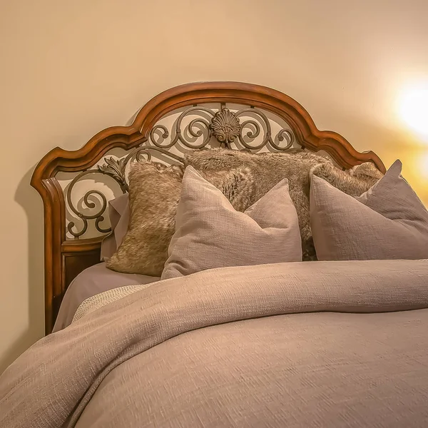 Bed with wood and wrought iron headboard inside the bedroom of a home