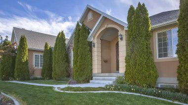 Mavi gökyüzü ve bulutlar altında ev cephesinde Panorama çerçeve Yard ve konik şekilli ağaçlar