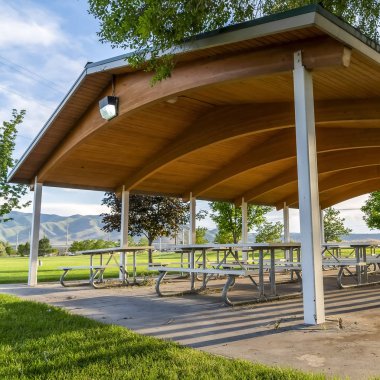 Kare çerçeve Piknik masaları ve banklar güneşli bir günde doğal bir parkta bir pavyon altında