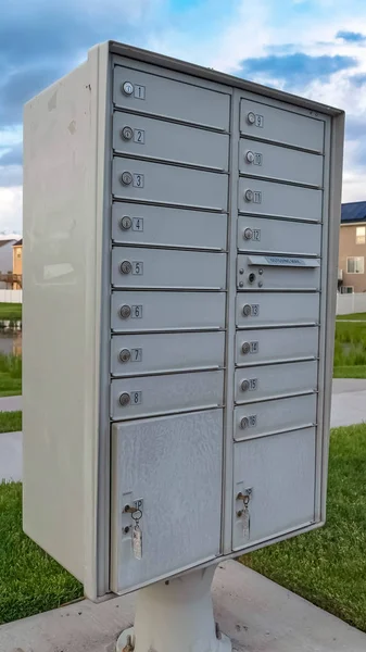 Вертикальная рамка Белый металлический кластер почтовый ящик с прудом травянистой местности и домов на заднем плане — стоковое фото