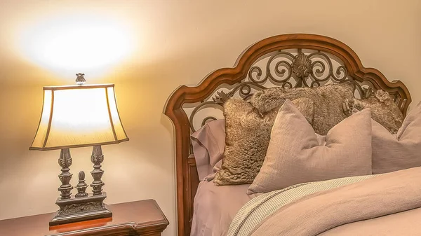 Panorama Bed with fluffy pillows against the wood and worught iron headboard