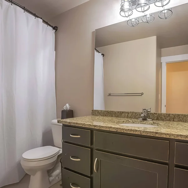 Туалет и инструмент Square Vanity прижались к белой стене хорошо освещенной ванной комнаты — стоковое фото