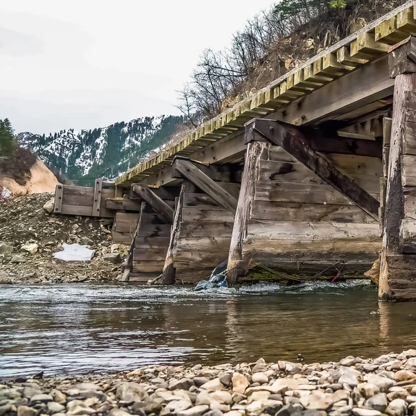 Квадратна рамка Румунський дерев'яний міст над кам'янистим струмком з блискучою водою — стокове фото