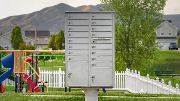 Panorama Caixa de correio de cluster de metal branco na calçada na frente de um playground colorido — Fotografia de Stock