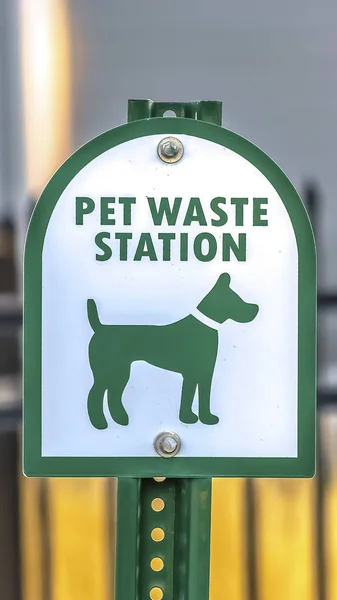 Vertical frame Close up of a Pet Waste Station with gate and building in the blurry background