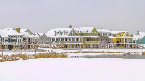 Panorama Hermosas casas frente a un lago plateado contra el cielo nublado en invierno — Foto de Stock