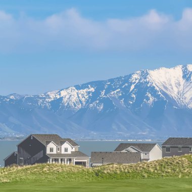 çerçeve Çimenli arazi ve güneşli bir günde mavi gökyüzü altında bir göl bakan evler