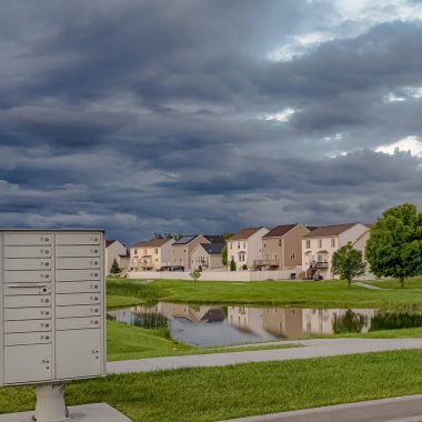 Square Sky geniş bir çimenli arazi ortasında evler ve gölet üzerinde gri bulutlar ile dolu