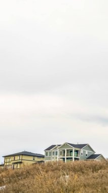 Dikey çerçeve Kışın karla kaplı dağda çok katlı ev üzerinde parlak bulutlu gökyüzü